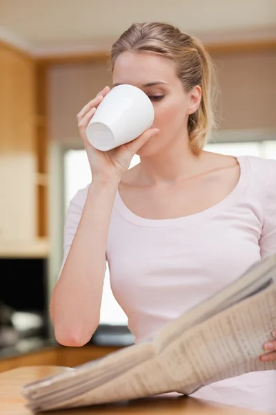 Portrait of a young woman reading the news while having tea — Stock Photo, Image