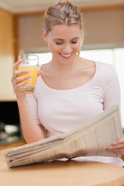 Portret kobiety czytania wiadomości podczas picia soku pomarańczowego — Zdjęcie stockowe