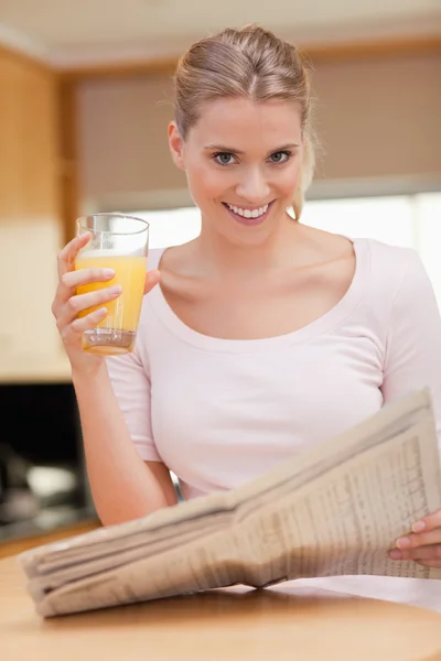 Портрет женщины, читающей новости во время питья сока — стоковое фото