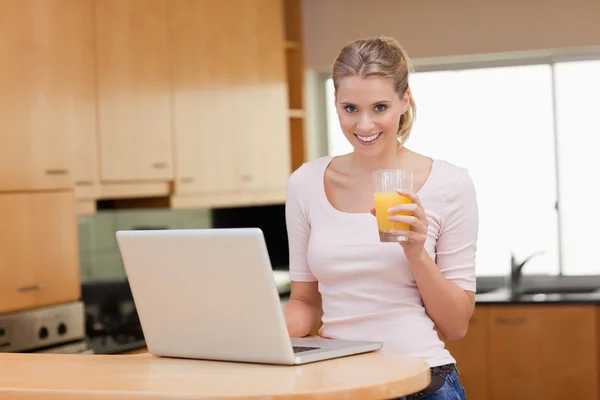 Woman using a notebook while drinking juice — Stock Photo, Image