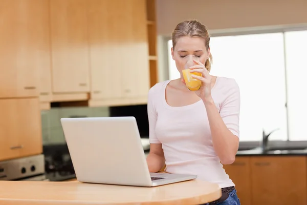 Γυναίκα χρησιμοποιώντας ένα σημειωματάριο πίνοντας χυμό πορτοκαλιού — Φωτογραφία Αρχείου