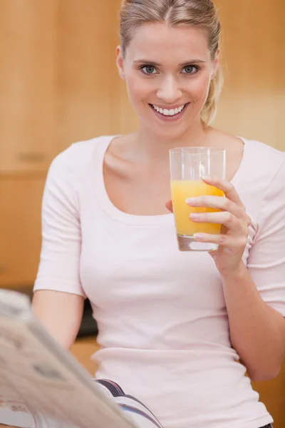 Retrato de una linda mujer leyendo las noticias mientras bebe jugo — Foto de Stock
