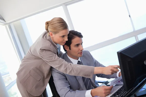 Managerin zeigt am Computer auf ihre Sekretärin — Stockfoto