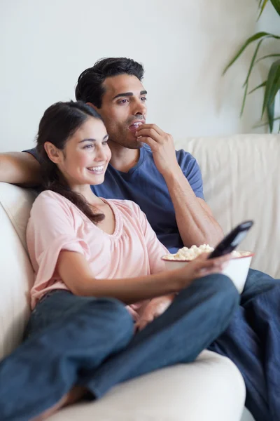Retrato de um casal assistindo TV enquanto come pipocas — Fotografia de Stock