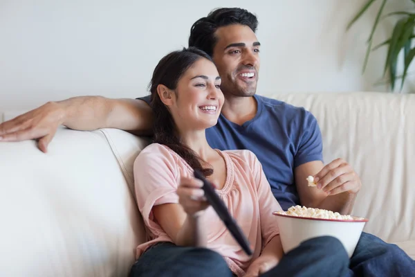 Пара смотрит телевизор, когда ест попкорн — стоковое фото