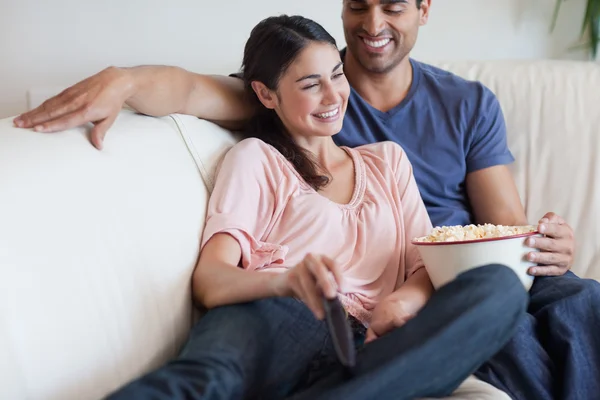 Zadowolona para oglądania tv jedząc popcorn — Zdjęcie stockowe