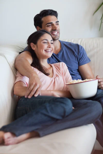 Retrato de um casal feliz assistindo televisão enquanto come popc — Fotografia de Stock