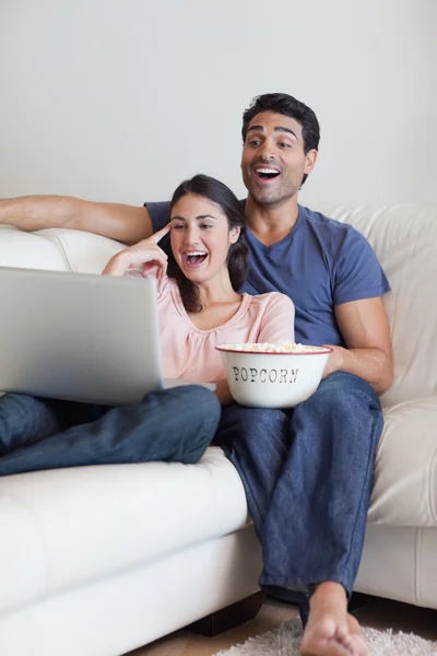 Retrato de una pareja riéndose viendo una película mientras come popc — Foto de Stock