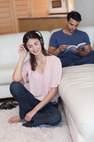 Portrait of a woman listening to music while her fiance is readi — Stock Photo, Image