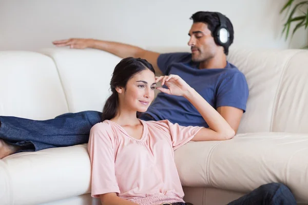 Woman watching TV while her husband is listening to music — Stock Photo, Image