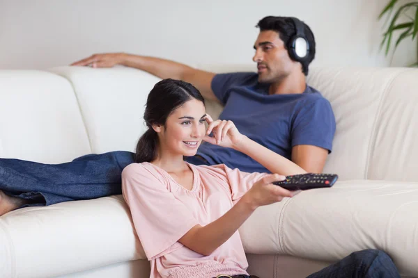 彼女のボーイ フレンドは音楽を聞いている間、テレビを見ている女性 — ストック写真
