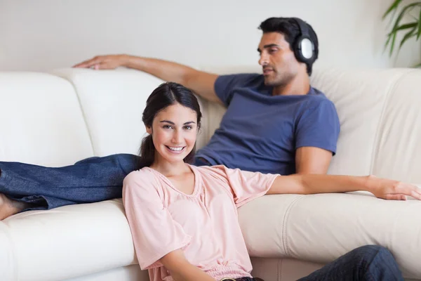 Young woman posing while her husband is listening to music — Stock Photo, Image