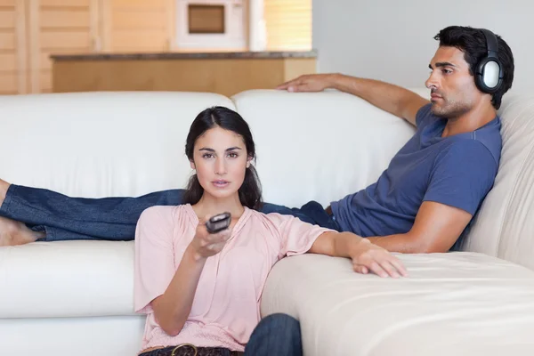 Vrouw televisie kijken terwijl haar vriendje naar mu luistert — Stockfoto