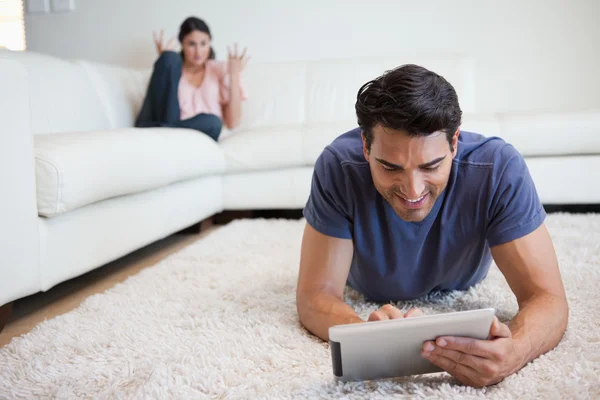 Man using a tablet computer while his girlfriend is getting mad — Stock Photo, Image