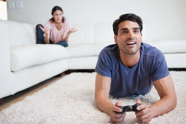 Man playing video games while his fiance is getting mad at him — Stock Photo, Image