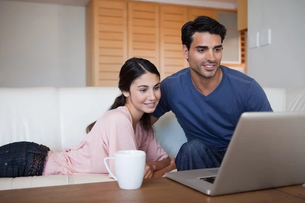 Casal jovem usando um laptop enquanto toma um café — Fotografia de Stock