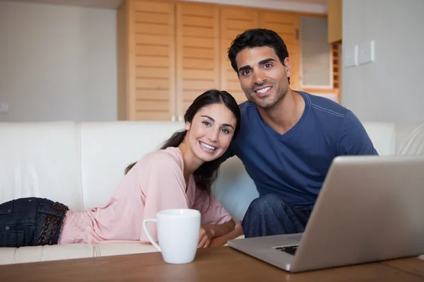 Casal sorrindo usando um laptop enquanto toma um chá — Fotografia de Stock