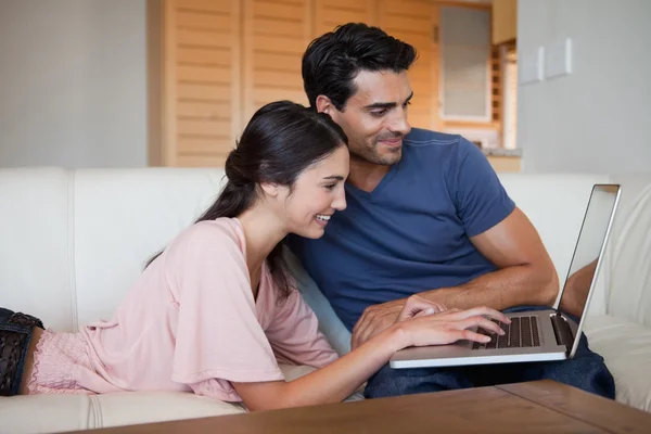 Sonriendo joven pareja usando un ordenador portátil — Foto de Stock