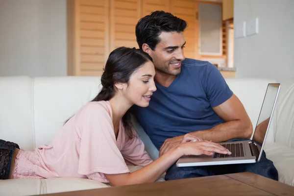 Encantadora pareja joven usando una computadora portátil — Foto de Stock