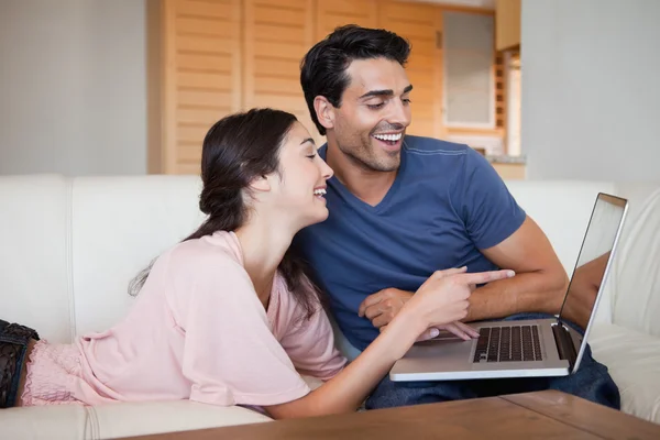 Riendo joven pareja usando un ordenador portátil — Foto de Stock
