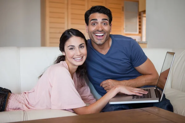 Skrattar unga par som använder en bärbar dator — Stockfoto