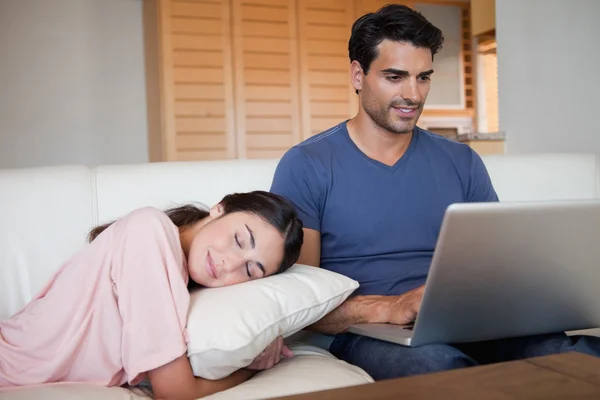 Man using a laptop while his fiance is sleeping — Stock Photo, Image