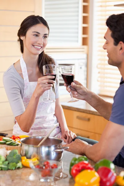 料理しながらワインのガラスを持っている若いカップルの肖像画 — ストック写真
