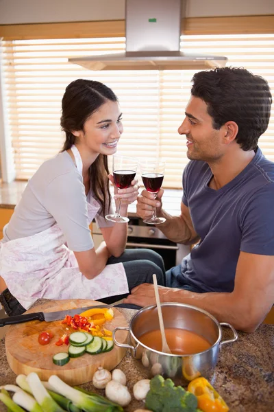 Retrato de um casal feliz tomando um copo de vinho enquanto cozinha — Fotografia de Stock