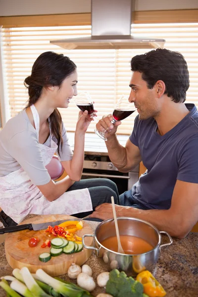 Ritratto di una coppia affascinante che beve un bicchiere di vino mentre cucina — Foto Stock