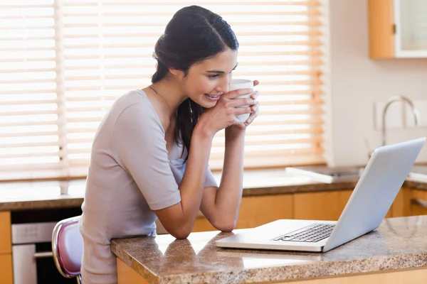 사랑 스러운 여자는 커피 한 잔을 마시는 동안 노트북을 사용 하 여 — 스톡 사진