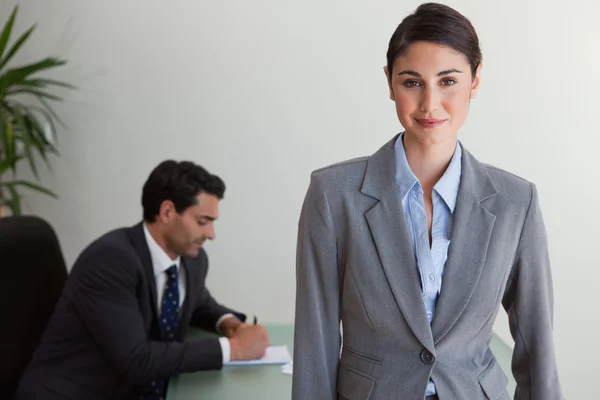 Schöne Geschäftsfrau posiert, während ihr Kollege arbeitet — Stockfoto