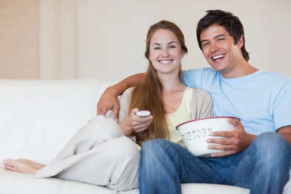 Пара смотрит телевизор, когда ест попкорн — стоковое фото