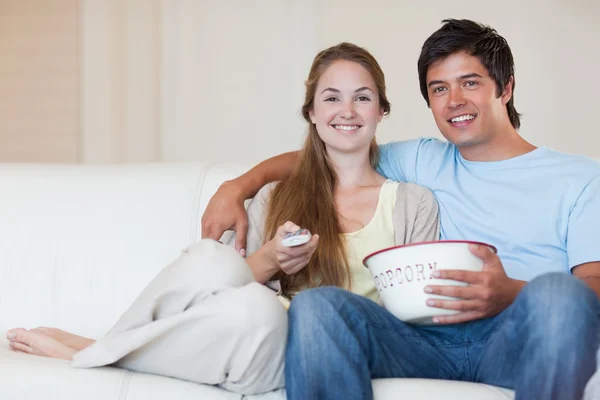 Mladý pár, sledování televize, zatímco jíst popcorn — Stock fotografie