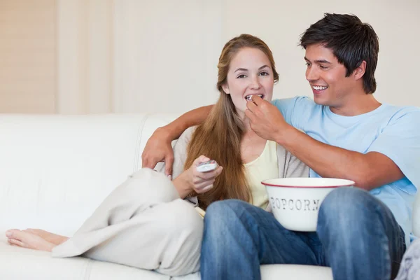 Lyckliga paret tittar på TV medan man äter popcorn — Stockfoto
