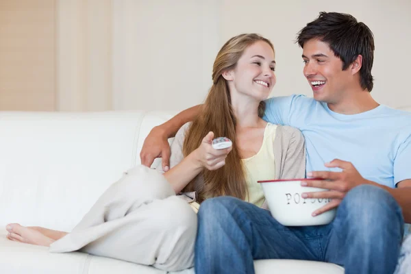 Affascinante coppia guardando la televisione mentre si mangia popcorn — Foto Stock