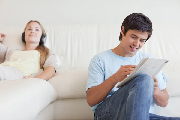 Mann macht Kreuzworträtsel, während sein Verlobter Musik hört — Stockfoto