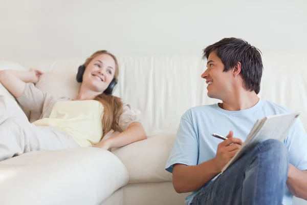 Man kruiswoordraadsels doen terwijl zijn vriendin is luisteren naar muziek — Stockfoto
