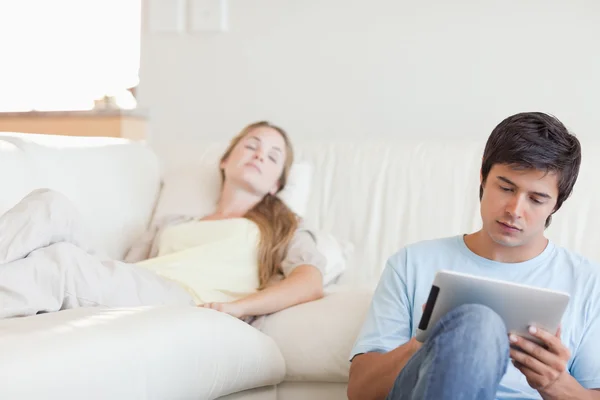 Muž pomocí tabletového počítače, zatímco jeho přítelkyně spí — Stock fotografie