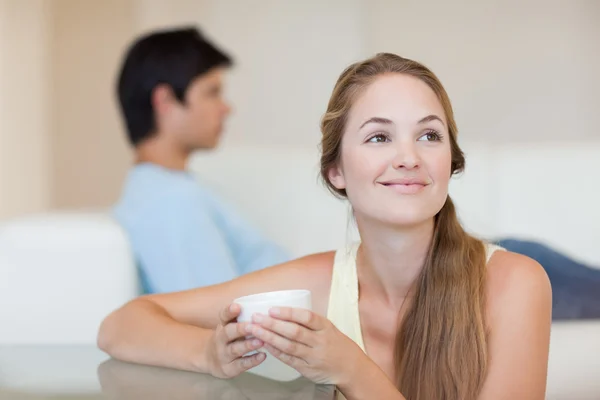 Mulher tomando um chá enquanto seu noivo está sentado em um sofá — Fotografia de Stock