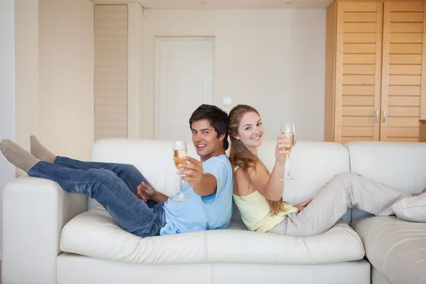 Par sitter rygg mot rygg med ett glas mousserande vin — Stockfoto
