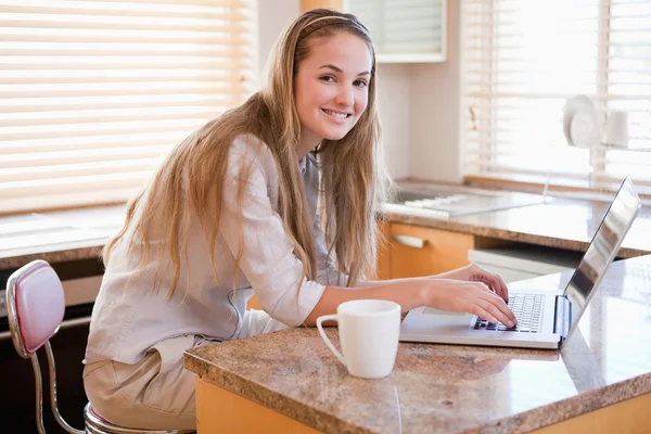 Mulher tomando café ao usar um laptop — Fotografia de Stock