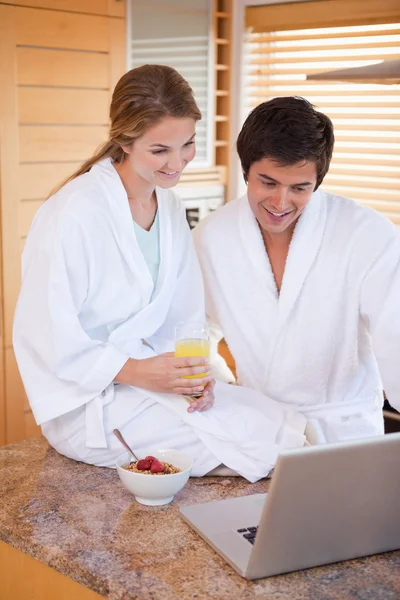 Porträt eines jungen Paares beim Frühstück mit einem Laptop — Stockfoto