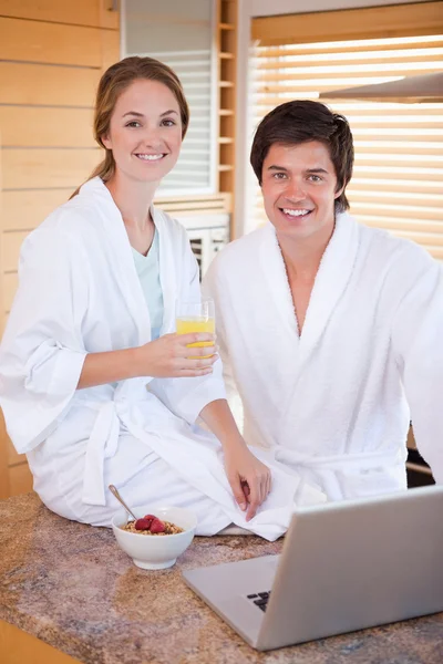 Retrato de una encantadora pareja desayunando mientras usa un —  Fotos de Stock