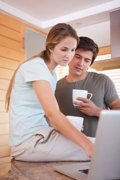Retrato de um casal tomando café enquanto usa um laptop — Fotografia de Stock