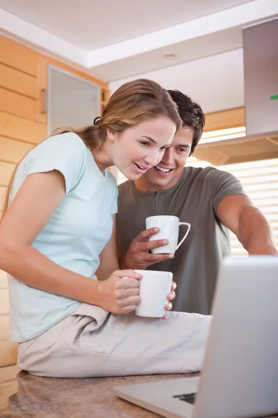Retrato de una pareja joven tomando té mientras usa una computadora portátil — Foto de Stock