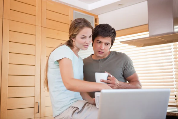 Пара пьет кофе во время использования ноутбука — стоковое фото