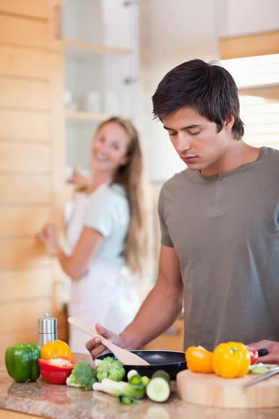Ritratto di un uomo che cucina mentre sua moglie lava i piatti — Foto Stock