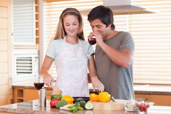 Giovane coppia cucinare la cena mentre beve vino rosso — Foto Stock