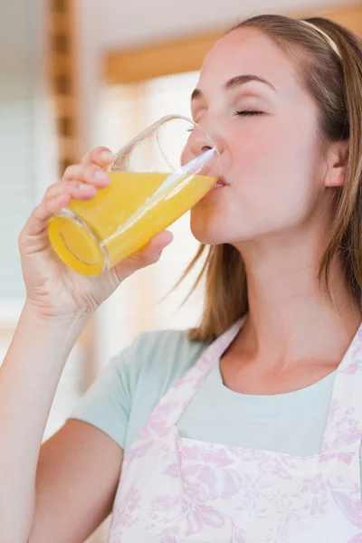 Retrato de uma mulher encantada bebendo suco de laranja — Fotografia de Stock