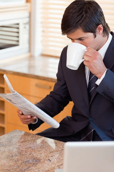 Portrait of a businessman drinking coffee while reading the news — Stock Photo, Image